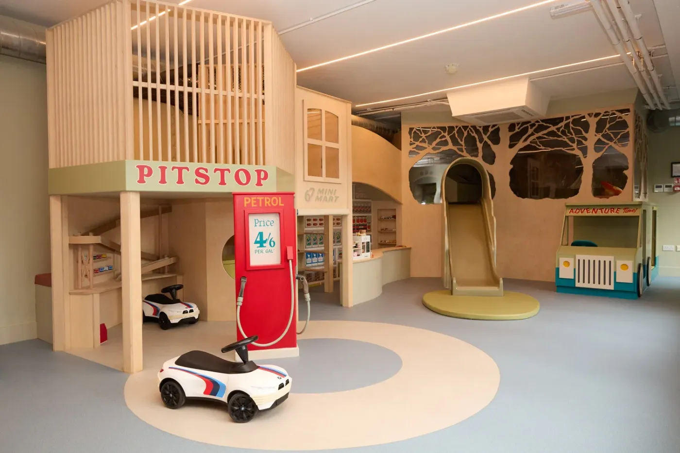 The Pitstop play space: a wooden clubhouse, red petrol pump, Mini Mart, slide and ride-on cars